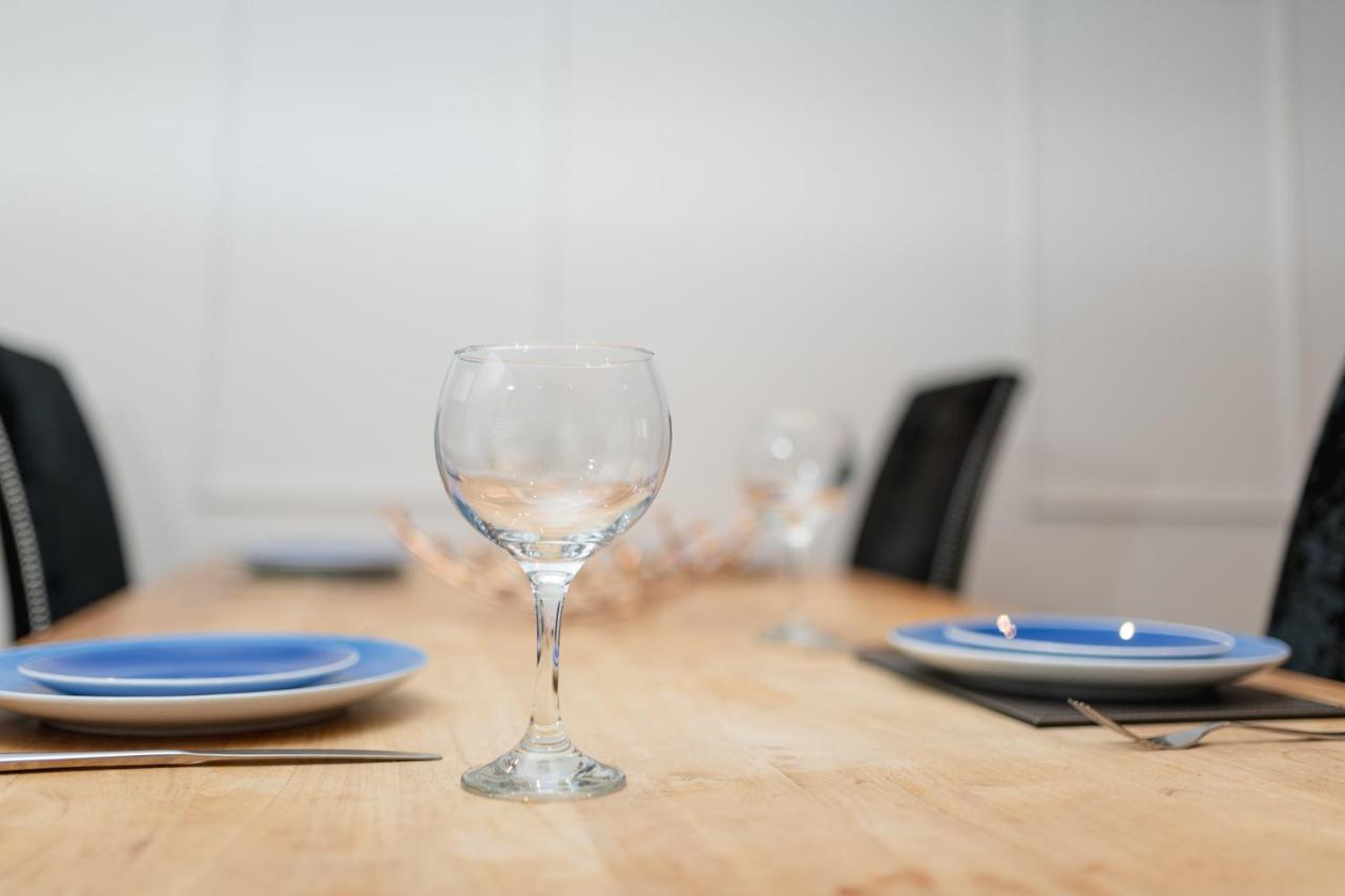 a table with two wine glasses and plates on it at Sidemersey Livings Liverpool Corporate & Relocation Apartment in Liverpool