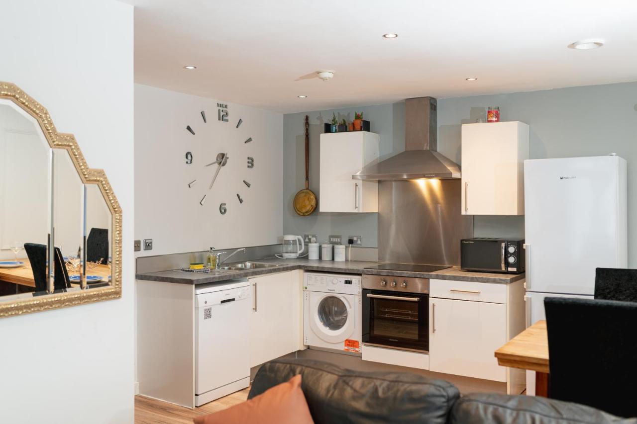 a kitchen with white cabinets and a clock on the wall at Sidemersey Livings Liverpool Corporate & Relocation Apartment in Liverpool