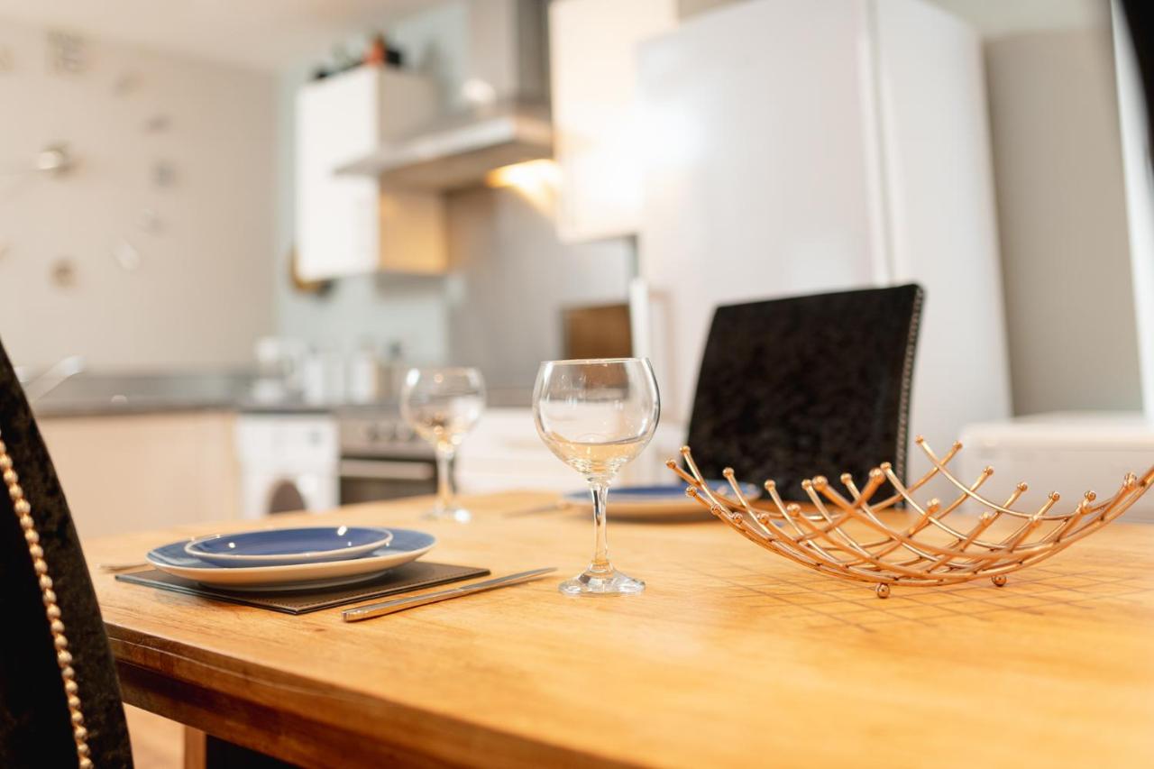a wooden table with two wine glasses on it at Sidemersey Livings Liverpool Corporate & Relocation Apartment in Liverpool