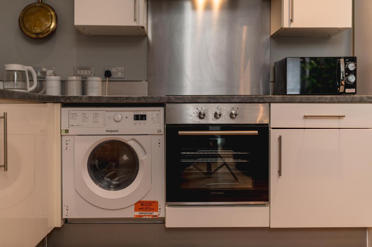 a kitchen with a stove and a washer and dryer at Sidemersey Livings Liverpool Corporate & Relocation Apartment in Liverpool